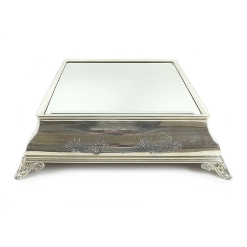 157 - An early 20th century silver plated wedding cake stand, of square form with bevelled mirror surface,... 