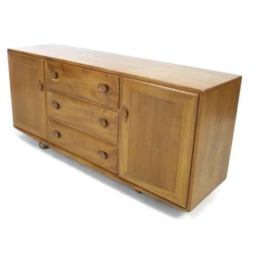 210 - An Ercol elm sideboard, with three central drawers flanked by two cupboards, all with recessed oval ... 