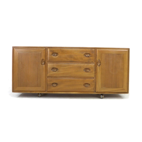 210 - An Ercol elm sideboard, with three central drawers flanked by two cupboards, all with recessed oval ... 