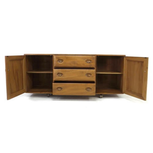 210 - An Ercol elm sideboard, with three central drawers flanked by two cupboards, all with recessed oval ... 