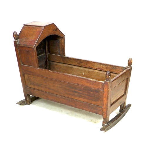 218 - A Victorian mahogany baby's crib, with finials to each corner, a shaped hood and raised on two rocke... 