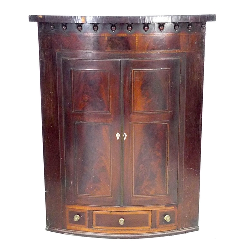 224 - An early Georgian mahogany bow fronted corner cupboard, unusual feather banding to the frize and fur... 