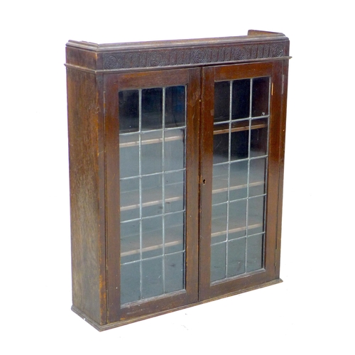 234 - A 1950s oak bureau bookcase, twin leaded glazed doors enclosing three shelves, fall front with fitte... 