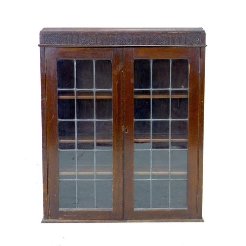 234 - A 1950s oak bureau bookcase, twin leaded glazed doors enclosing three shelves, fall front with fitte... 