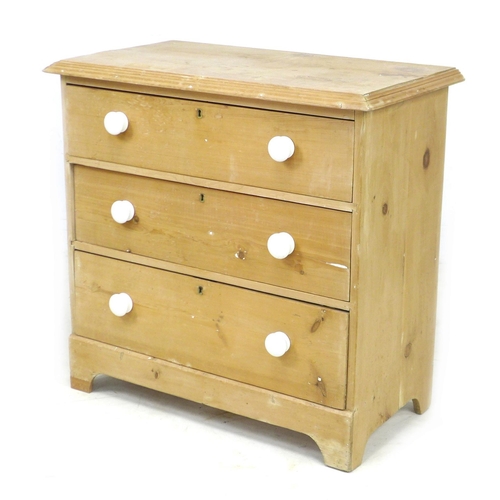 241 - An early 20th century pine chest of three drawers, raised on bracket feet with white ceramic handles... 