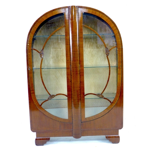 256 - A 1930s oak veneered bookcase,  with domed top and twin glazed doors, enclosing three adjustable she... 