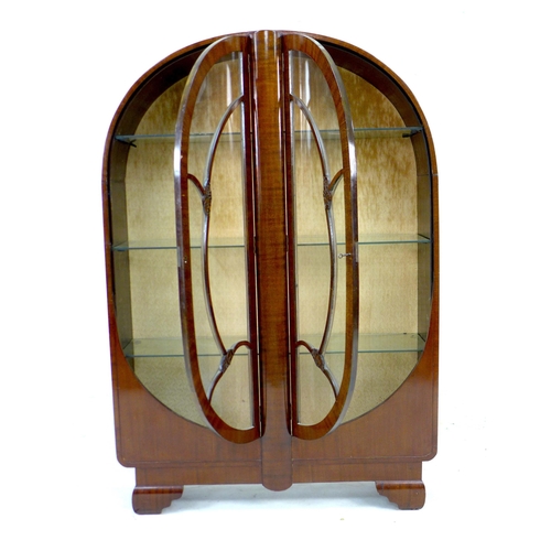 256 - A 1930s oak veneered bookcase,  with domed top and twin glazed doors, enclosing three adjustable she... 