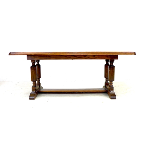 283 - A mid 20th century oak trestle dining table, rectangular top with canted corners and moulded reeded ... 