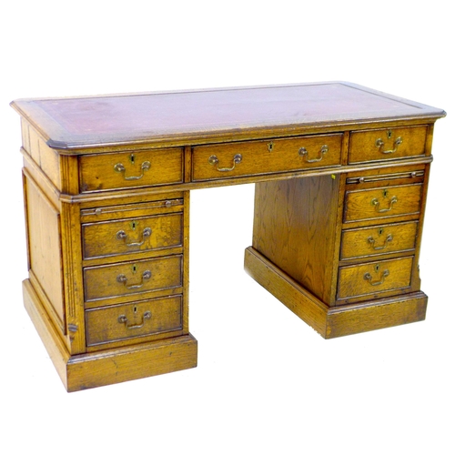 284 - A reproduction oak pedestal desk, in George III style, inset red leather surface, the nine drawers w... 