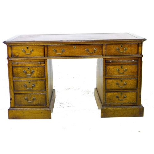 284 - A reproduction oak pedestal desk, in George III style, inset red leather surface, the nine drawers w... 