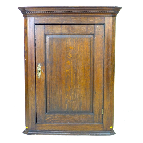 288 - A George III oak corner cupboard, with a blind carved frieze over a single flat front fielded panel ... 