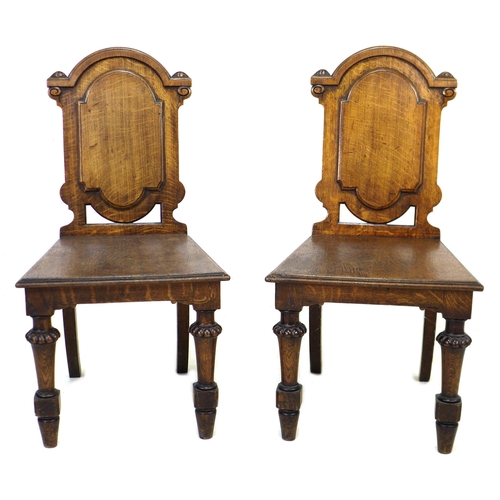 291 - A pair of Victorian oak hall chairs, with fielded panel backs, raised on lobe carved front legs and ... 