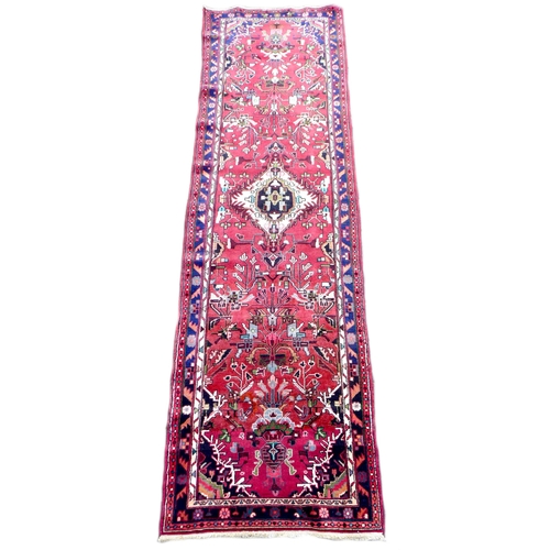 311 - A Heriz runner with red ground, with central cream coloured diamond medallion, on a densely decorate... 