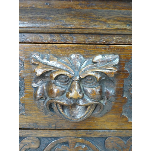 323 - A Victorian stained oak sideboard, the front carved with green man face masks, blind friezes of flow... 