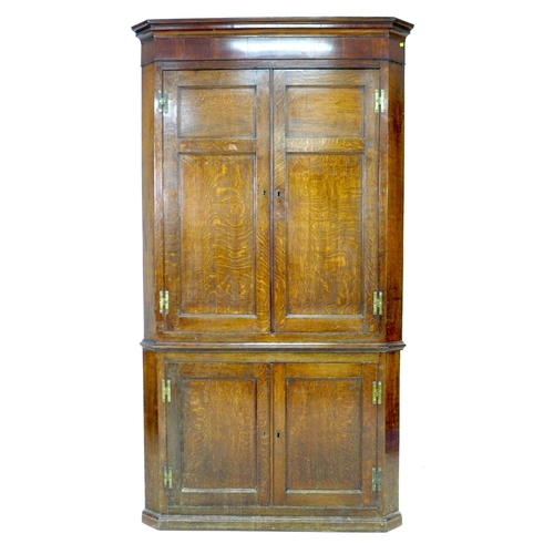 336 - A George III oak and mahogany corner cupboard, floor-standing, with panelled doors and shelved inter... 