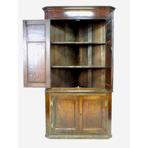 336 - A George III oak and mahogany corner cupboard, floor-standing, with panelled doors and shelved inter... 