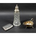 A group of three silver items, comprising a cut glass silver topped sugar sifter, 18cm high, a milk ... 