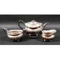 An George V silver three piece tea service, with faceted bodies and fruiting vine cast rims, compris... 
