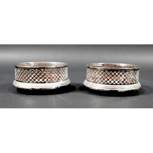 13 - A pair of ERII silver wine bottle coasters, with pierced lattice sides and turned mahogany bases ins... 