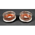 A pair of ERII silver wine bottle coasters, with pierced lattice sides and turned mahogany bases ins... 