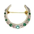 A platinum, diamond and emerald crescent brooch, formed of seven graduated emeralds, largest 3mm dia... 