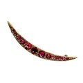 A 9ct rose gold and red stone crescent brooch, the graduated stones interpersed with diamond chips, ... 