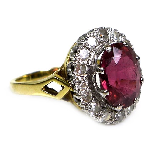 282 - An 18ct yellow gold dress ring, set with an oval cut red/purple coloured stone, approximately 10 by ... 