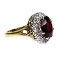 An 18ct yellow gold dress ring, set with an oval cut red coloured stone, possibly garnet, approximat... 