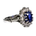 An 18ct white gold dress ring, set with an oval cut sapphire, approximately 8 by 6 by 5mm, surrounde... 