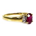 An 18ct gold and ruby ring, the oval cut stone approximately 7 by 5 by 3.5mm, flanked by six 1.5mm d... 
