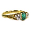 An unmarked gold, diamond and emerald three stone ring, with a central emerald cut Colombian emerald... 
