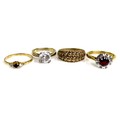 A group four rings, comprising an 18ct gold flowerhead ring, set centrally with a round cut red ston... 