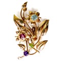 A 9ct gold foliate design brooch, inlaid with multicoloured stones of varying sizes, with safety cha... 
