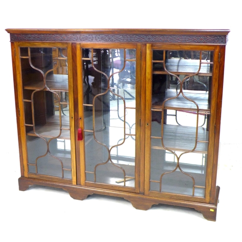 242 - An Edwardian mahogany bookcase, blind carved frieze above three glazed doors, enclosing shelves, mir... 