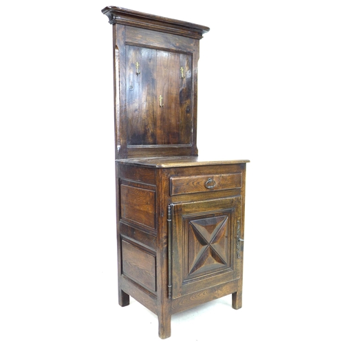 245 - An early 19th century French oak wash stand, its top section with later fitted brass coat hooks, its... 