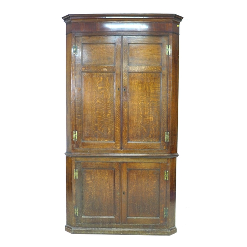 275 - A George III oak and mahogany corner cupboard, floor-standing, with panelled doors and shelved inter... 