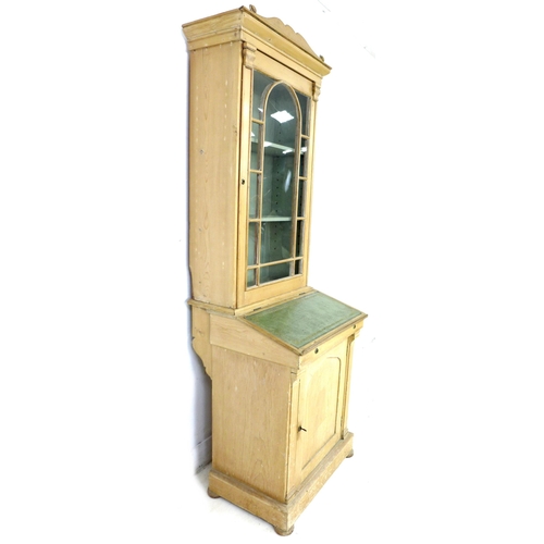 283 - A 19th century French stripped pine bureau bookcase, with shaped pediment over a single glazed door,... 