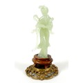 A Chinese carved jade figure, late 20th century, modelled as a lady in standing pose, on a turned wo... 