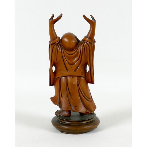 35 - A Chinese carved wooden figure of a Buddha, modelled standing with his arms raised, on a turned base... 