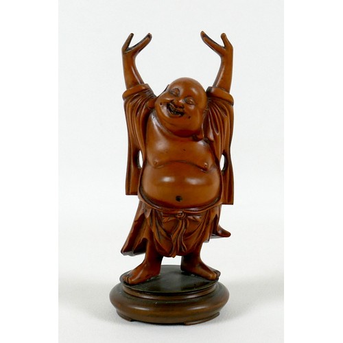 35 - A Chinese carved wooden figure of a Buddha, modelled standing with his arms raised, on a turned base... 