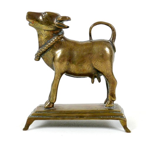 31 - A 19th century Indian brass ornament, modelled as a cow in standing pose with head raised, with engr... 