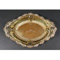 An Edwardian silver gilt commemorative bowl, of boat form with pierced sides and repousse scrolls to... 