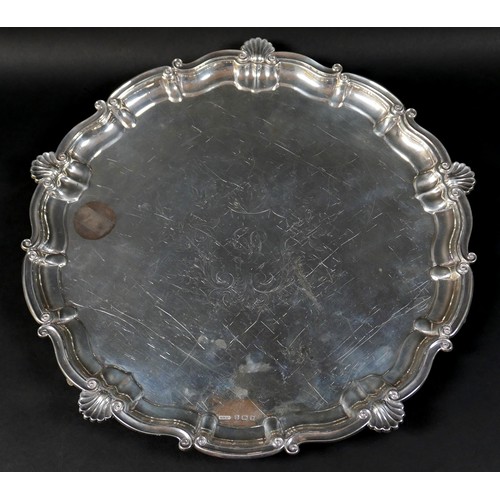 121 - A silver tray, circular form with scalloped edge, engraved decoration, raised on three feet, 3 by 35... 