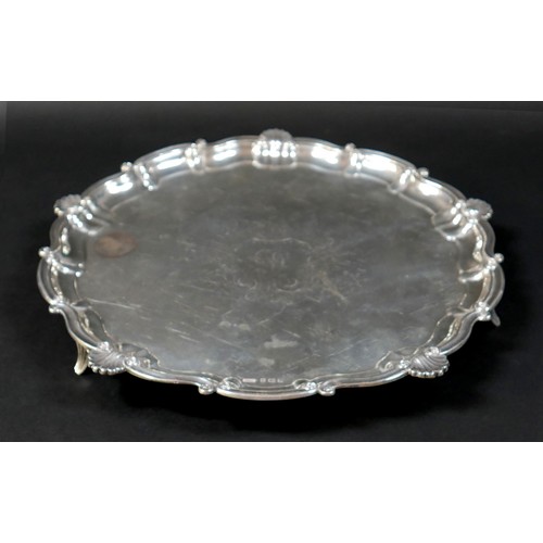 121 - A silver tray, circular form with scalloped edge, engraved decoration, raised on three feet, 3 by 35... 