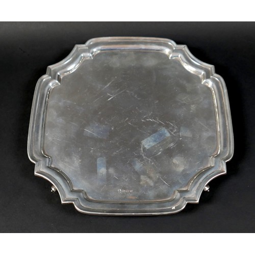 98 - A silver tray, of square form with incuse corners, raised upon four scroll feet, 3 by 26.5cm, 21.7to... 