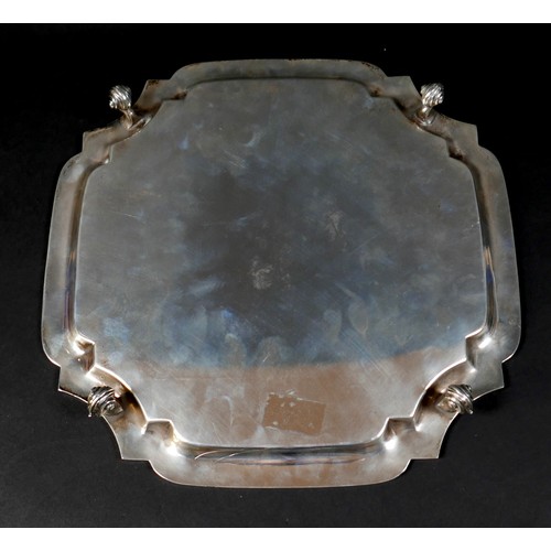 98 - A silver tray, of square form with incuse corners, raised upon four scroll feet, 3 by 26.5cm, 21.7to... 