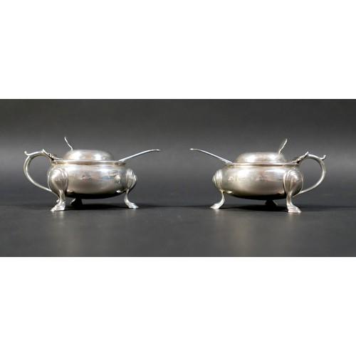 23 - A pair of silver lidded mustard pots, of cauldron form with scroll handle and attached thumb pieces,... 