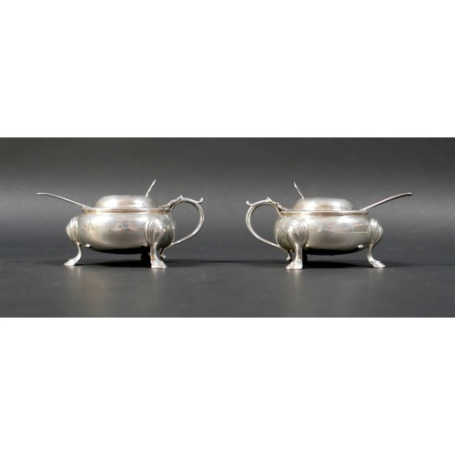 23 - A pair of silver lidded mustard pots, of cauldron form with scroll handle and attached thumb pieces,... 