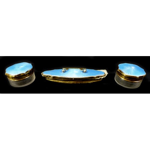 49 - A cased silver dressing table set, serpentine edge lid with silver gilt and blue enamel decoration, ... 