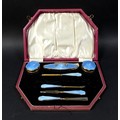 A cased silver dressing table set, serpentine edge lid with silver gilt and blue enamel decoration, ... 